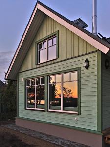哈普萨卢Holmi Maja的绿色房子,带窗户,日落