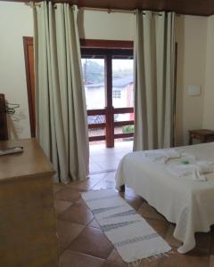 塔里图巴Estalagem São Gonçalo的一间卧室设有一张床和一个滑动玻璃门