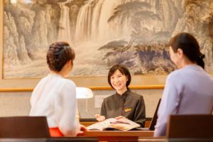 那须町Hotel Shiki no Yakata Nasu的和两名妇女一起坐在桌子上的女人