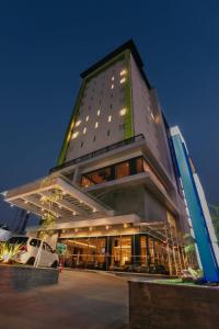 泗水泗水高级商务酒店的一座高大的建筑,前面有一辆汽车