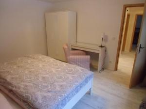 拉德博伊尔Ferienwohnung Simone的一间卧室配有一张床、一张桌子和一把椅子