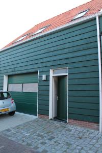 科莱恩斯普拉特Het Bakkersschuurtje的绿色的建筑,有门和汽车