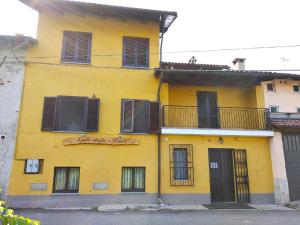 Candia CanaveseSpighe Paglia e Girasole的黄色的建筑,设有黑窗和阳台