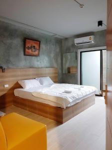 Samut SakhonSands Place Apartment and Hotel的一间卧室设有一张大床和一张黄色凳子