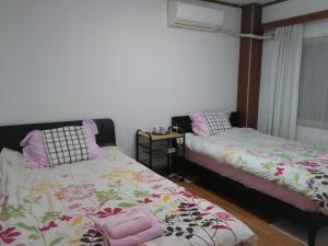大阪大阪库马楼旅馆的一间卧室设有两张床和窗户。