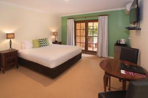 玛格丽特河平达旅馆的一间卧室配有一张床、一张桌子和一张桌子