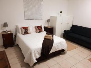 EshoweAfrican Dwarf Kingfisher Guesthouse的卧室配有白色的床和黑色沙发