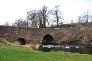 克里夫Bridgehill Cottage Bed & Breakfast的田野上一条河上的石桥