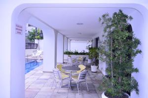 瓜鲁雅Ap Enseada Lado Praia Ar Cond Piscina Wi-Fi 500Mb的庭院配有桌椅和植物