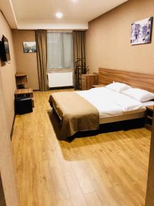 第比利斯Lords Hotel的一间卧室设有一张大床,铺有木地板