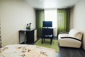 新库兹涅茨克Apart Inn的酒店客房配有一张床、一把椅子和一台电视。