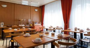 巴黎科斯莫特尔酒店的餐厅设有木桌和椅子,并备有杯子