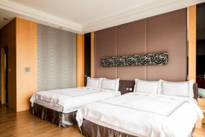 Tuku云林商务旅馆的配有白色床单的酒店客房内的两张床