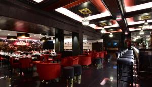 里斯本Maxime Hotel Lisbon的一间设有红色桌椅的餐厅和一间酒吧