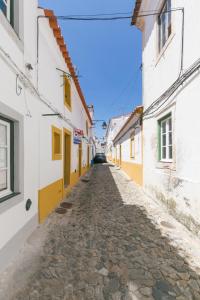 埃武拉Casa Candeias的一座白色和黄色建筑的小镇上的小巷