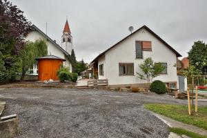 OberessendorfZimmervermietung Familie Kolb的一座白色的房子,有橙色的门和教堂