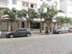 巴拉奈里奥-坎布里乌Apartamento Confortavel em Balneário Camboriu的三辆汽车停在一座棕榈树建筑前面