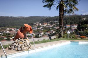 圣托·蒂尔索Casa Rural do Salgueirinho的一座奶牛雕像,在游泳池旁边挂着帽子