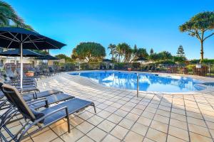 黄金海岸Golden Riviera Absolute Beachfront Resort的一个带躺椅和遮阳伞的游泳池