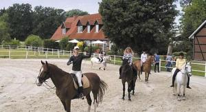 赫曼斯堡Heidehotel Gut Landliebe Restaurant Montags Ruhetag!的一群人骑着马在泥土上