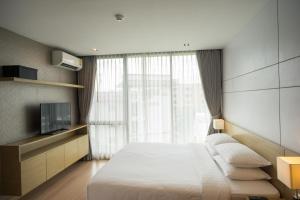 清迈Sanae' Hotel Nimman的一间卧室配有一张大床和电视