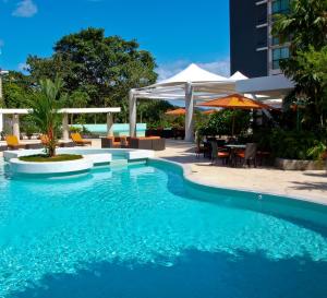 ParaísoSummit Rainforest Golf Resort & All Inclusive的毗邻带桌子和遮阳伞的游泳池