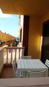La Playa CaleraAPARTAMENTOS EL CIENO的阳台上配有白色的桌椅