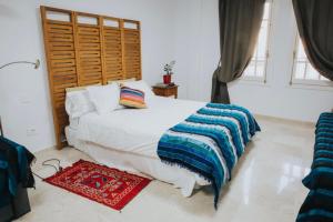 圣克鲁斯-德特内里费Home Bassou的卧室配有白色的床和木制床头板