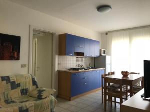 利多迪耶索罗Appartamenti Aquamarina的厨房以及带蓝色橱柜和沙发的客厅。