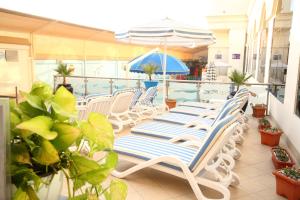 沙迦Lavender Hotel Sharjah的一个带游泳池的阳台的一排躺椅