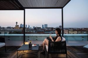 米兰贝斯特韦斯特城市酒店的坐在阳台上喝一杯葡萄酒的女人