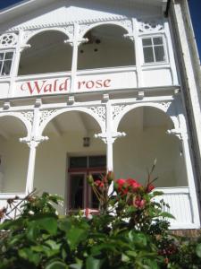 奥斯赛拜-塞林Pension Waldrose的上面有一面墙的玫瑰花标志的白色建筑