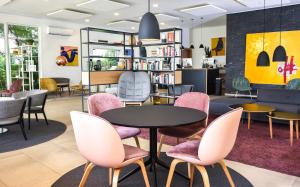 阿布贾Nordic Hotel Abuja的一个带粉红色椅子、桌子和书架的图书馆