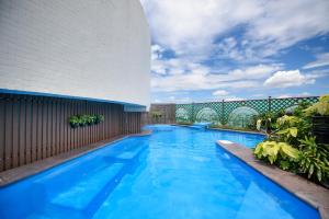 曼谷Grand China Bangkok的一座大型蓝色游泳池,位于大楼旁边