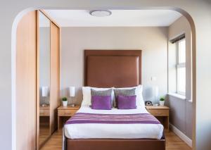 雷丁城墙楼 - 费舍尔之家公寓的一间卧室配有一张带紫色枕头的大床