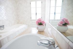 阿雷内拉Villa Vincenza的浴室设有水槽和两瓶粉红色花卉