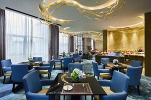 齐齐哈尔齐齐哈尔万达嘉华酒店的一间配备有桌子和蓝色椅子的用餐室
