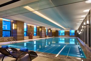 齐齐哈尔齐齐哈尔万达嘉华酒店的酒店客房的大型游泳池配有椅子