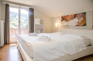 格林德尔瓦尔德Chalet D的白色的卧室设有一张白色大床和一个窗户。