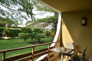 布琼布拉Hotel Club du Lac Tanganyika的阳台的门廊配有桌椅