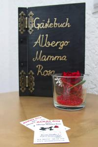 文西德尔Hotel Albergo Mamma Rosa的一张桌子,上面有标志和一碗红玫瑰