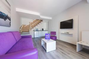 马斯帕洛马斯eó Maspalomas Resort的客厅配有紫色沙发和电视