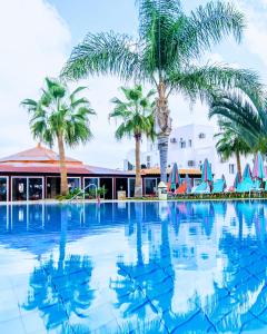 玛利亚Yiannis Manos Hotel Resort的一座大型游泳池,在一座建筑前种有棕榈树
