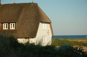 兰图姆瓦特霍夫酒店的海边的白色房子,带茅草屋顶