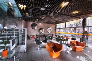 布拉格布拉格大都会酒店的餐厅设有橙色椅子和桌子以及窗户。