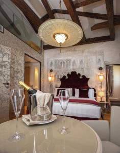 威尼斯圣克罗斯精品酒店的一间卧室配有一张床和一张带酒杯的桌子
