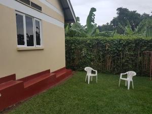 恩德培Wemofa Pad Self-Catering Apartment的两把椅子坐在房子旁边的草上