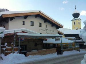 萨尔巴赫Haus Willibald的雪中带钟楼的房子