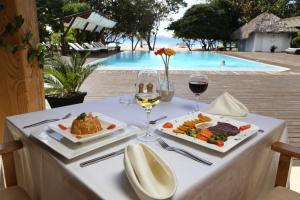 蓬塔露奇亚Punta Rucia Lodge Hotel Boutique & Spa的一张带食物和葡萄酒的桌子和一个游泳池