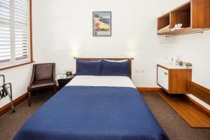 科夫斯港Pier Hotel Coffs Harbour的一间卧室配有蓝色的床和一张书桌